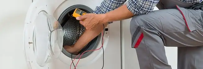 Dryer repair technician inspecting and repairing a clothes dryer in Des Moines, IA