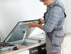 Appliance repair technician installing a built-in cooktop in Des Moines, IA