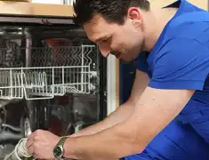 Dishwasher repair technician inspecting and servicing an open dishwasher in Des Moines, IA