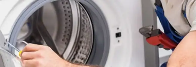 Appliance technician repairing a clothes dryer drum and internal parts in Des Moines, IA