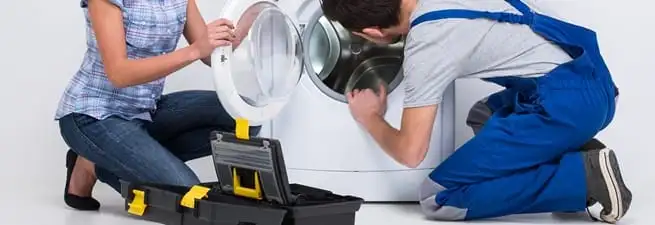 Washer repair technician inspecting a front-load washing machine with tools in Des Moines, IA