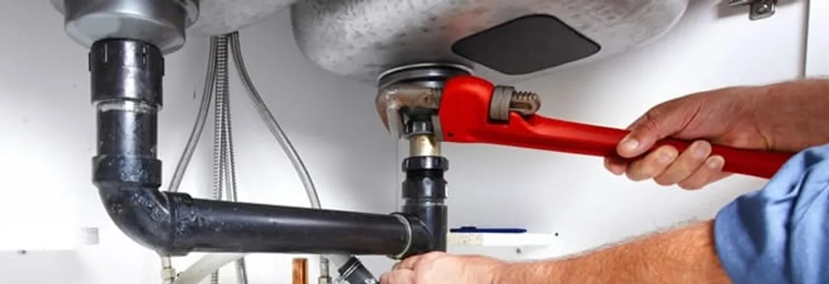 Garbage disposal repair technician tightening the sink drain and disposal connection in Des Moines, IA