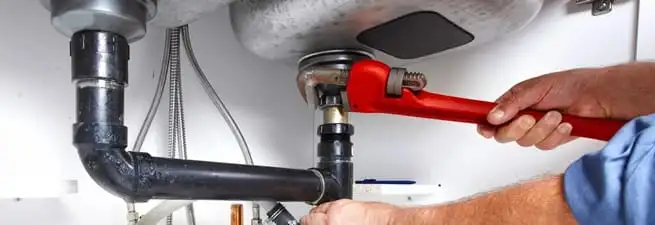 Garbage disposal repair technician tightening the sink drain and disposal connection in Des Moines, IA
