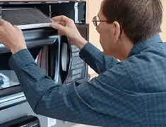 Appliance repair technician replacing a microwave vent filter in Des Moines, IA