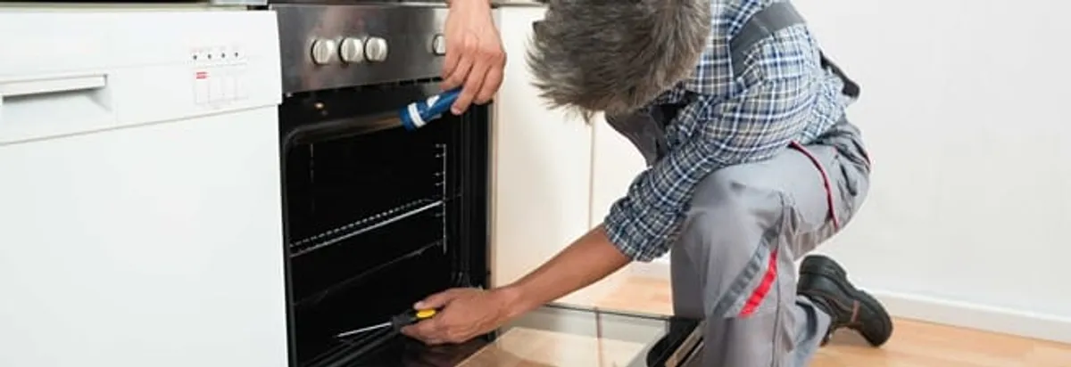 Oven repair technician inspecting and servicing an electric oven in Des Moines, IA