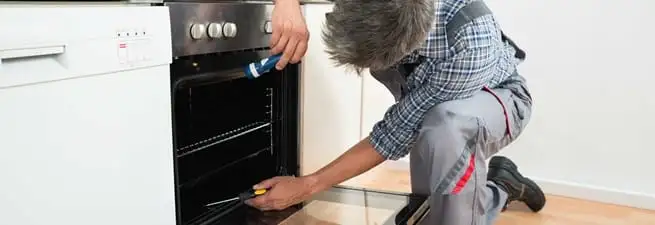 Oven repair technician inspecting and servicing an electric oven in Des Moines, IA