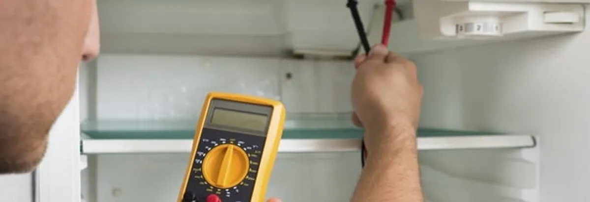 Refrigerator repair technician testing electrical components with a multimeter in Des Moines, IA