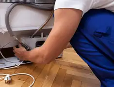 Appliance repair technician fixing refrigerator water line and connections in Des Moines, IA