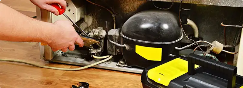 Refrigerator repair technician fixing the compressor and wiring in Des Moines, IA