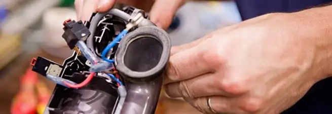 Vacuum repair technician reconnecting wiring and components in Des Moines, IA