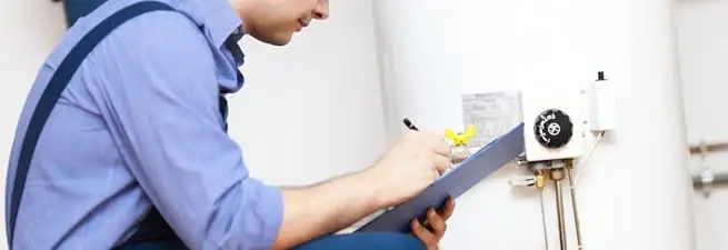 Water heater repair technician inspecting the unit and recording service notes in Des Moines, IA